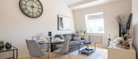 Una sala moderna con comedor, un reloj de pared grande y una ventana con luz natural.
