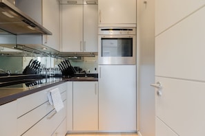 A modern kitchen with stainless steel appliances, white cabinetry, and a black countertop.
