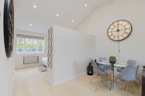 A modern dining area with a round table, chairs, and a wall clock. - Newly Renovated 1BDR in Knightsbridge with WiFi (London)