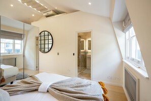 A modern bedroom with a large bed, a walk-in closet, and a bathroom with a glass shower. - Newly Renovated 1BDR in Knightsbridge with WiFi (London)