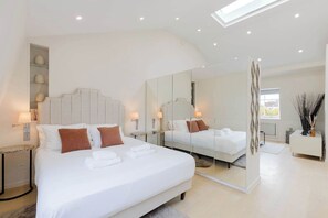 A modern hotel room with a large bed, a mirror, a bedside table, and a small side table. - Newly Renovated 1BDR in Knightsbridge with WiFi (London)