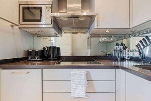 Una cocina moderna con microondas integrado, campana extractora de acero inoxidable y una isla grande con pileta y cajones de almacenamiento.