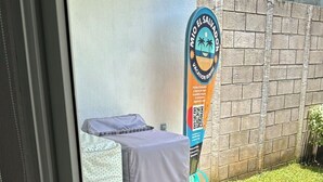 A room with a bed covered in a white sheet, a small table with a cloth, and a QR code on a sign. - Silvia House II Acropoli Sonsonate. (Sonsonate)