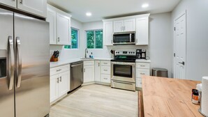 Eine moderne Küche mit weißen Schränken, Edelstahlgeräten und einer Holz Arbeitsplatte.