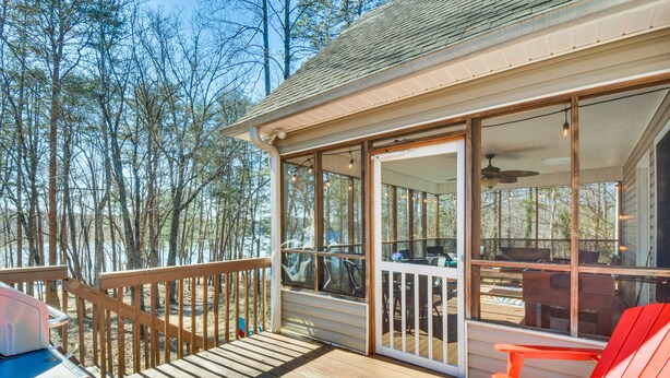 Eine Holzterrasse mit überdachter Sitzgelegenheit, einem roten Adirondack-Stuhl und einem Grill.