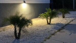 A residential building with a well-lit exterior, a gravel pathway, and small palm trees. - The Mermaid at Auberge d'Amelia (Fernandina Beach, FL)