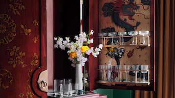 Een houten kast met bloemversieringen, een vaas met bloemen en een plank met glazen.
