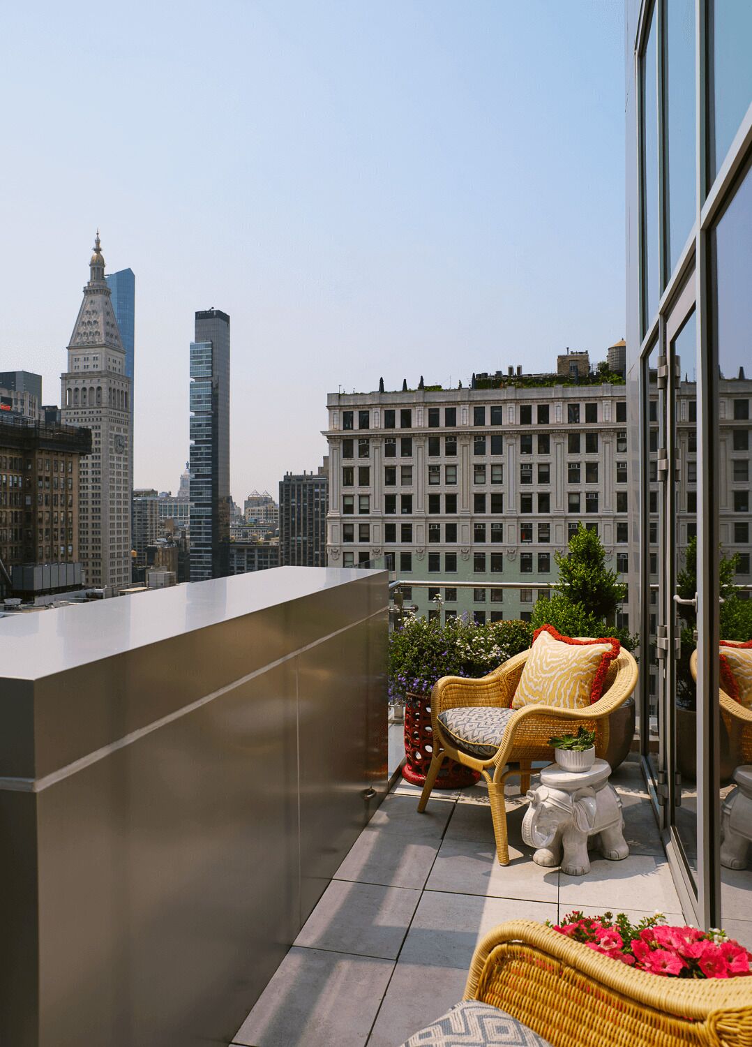 A balcony with wicker furniture, a potted plant, and a decorative elephant statue.