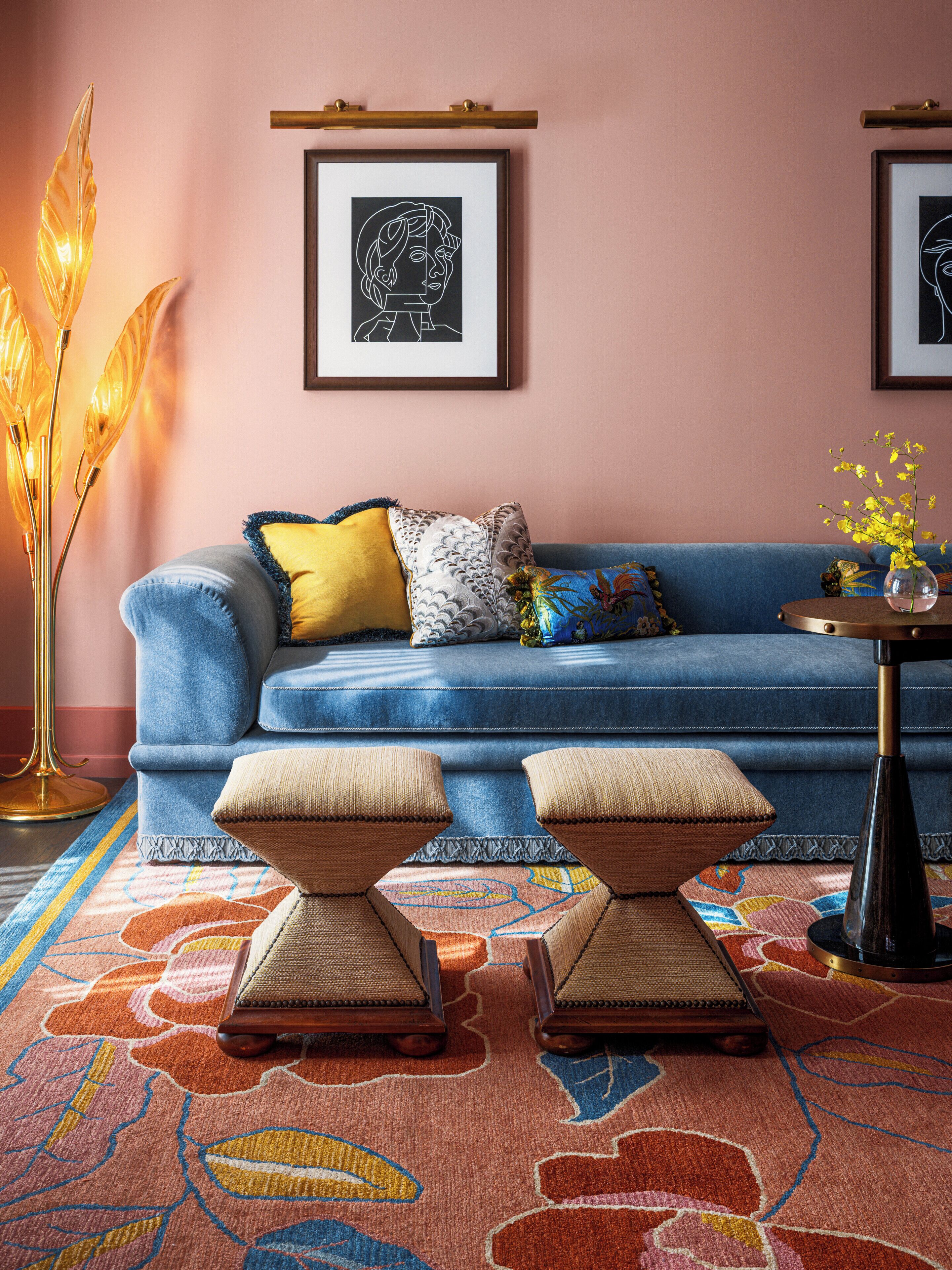 A blue sofa with a yellow pillow, a patterned rug, and a floor lamp.