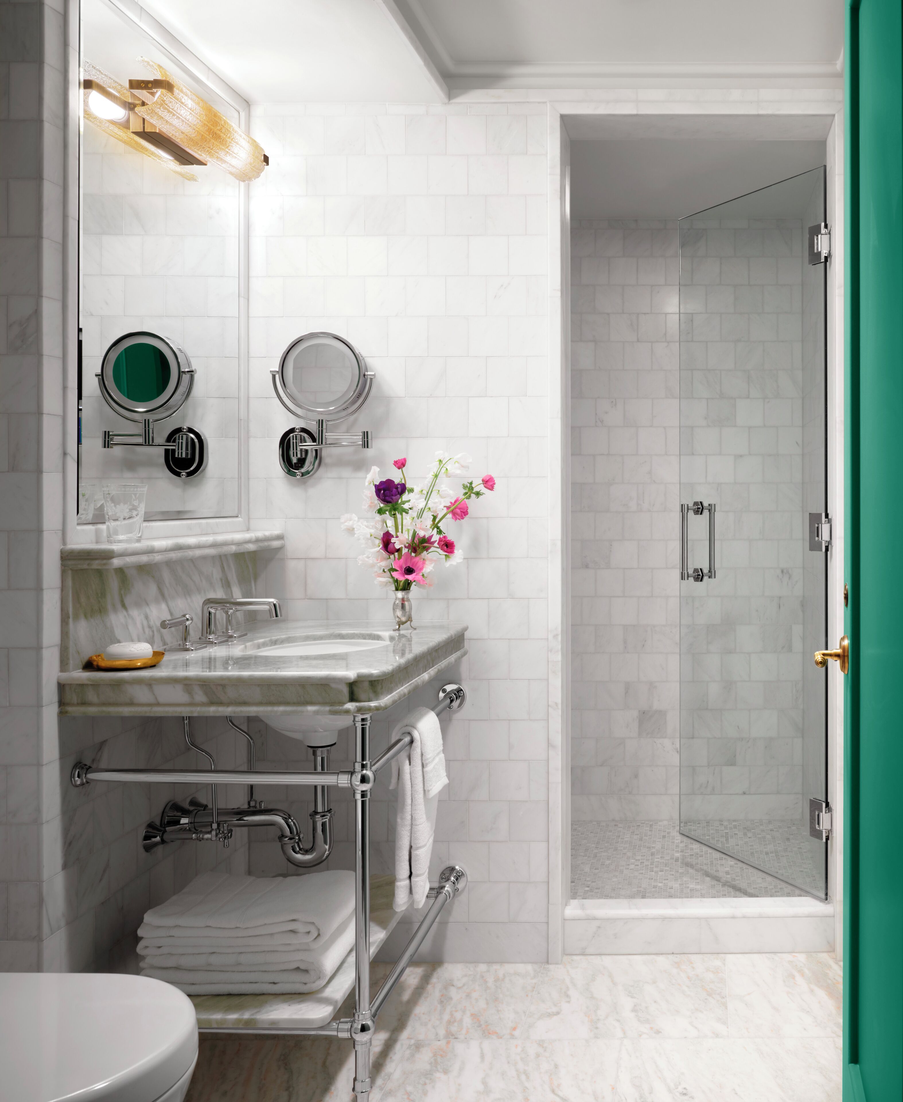 A bathroom with a sink, two mirrors, a toilet, and a shower area.