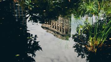 A reflection of a building in a calm body of water surrounded by greenery.