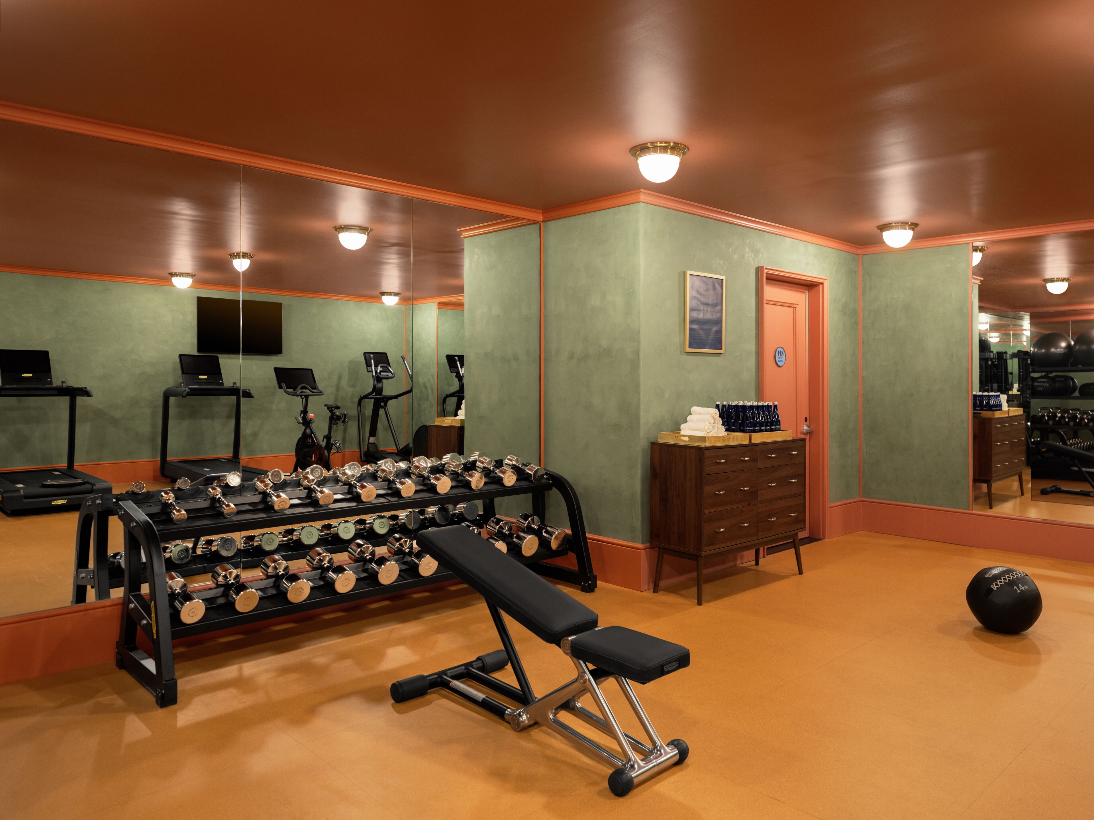 A gym with exercise equipment, a bench, and a mirror.