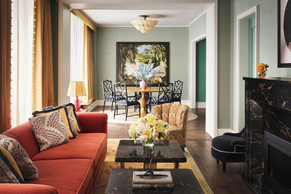 A living room with a sofa, a coffee table, a fireplace, and a dining area with chairs and a table.