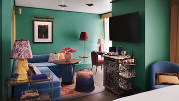 Una sala de estar moderna con paredes verde azulado, un sofá azul, una mesa de centro y un televisor montado en la pared.