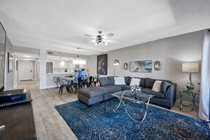 Una sala de estar moderna con un sofá modular, una mesa de centro de vidrio y un tapete azul estampado.