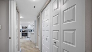 A hallway leading to a kitchen with white cabinetry and a microwave. - 🌊Beachfront Paradise: 3BR Condo with Pool & Balcony in Indian Rocks Beach-RC 309! (Indian Rocks Beach)