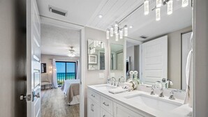 A modern bathroom with a double sink, large mirror, and a view of the balcony. - 🌊Beachfront Paradise: 3BR Condo with Pool & Balcony in Indian Rocks Beach-RC 309! (Indian Rocks Beach)