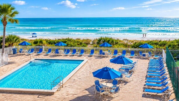 A pool area with a view of the beach, lounge chairs, and umbrellas. - 🌊Beachfront Paradise: 3BR Condo with Pool & Balcony in Indian Rocks Beach-RC 309! (Indian Rocks Beach)