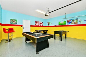 A pool table with a red chair, a foosball table, and colorful wall art. - Best Value Disney Pool/Spa Home! No Carpet! No back neighbor! Resort Amenities! (Davenport)