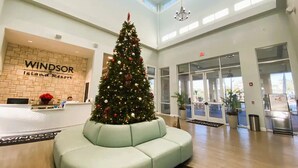 A reception area with a Christmas tree, a light green sofa, and a Windsor Island Resort sign.