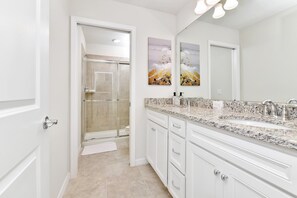 A modern bathroom with a glass-enclosed shower, white cabinetry, and a granite countertop. - Best Value Disney Pool/Spa Home! No Carpet! No back neighbor! Resort Amenities! (Davenport)