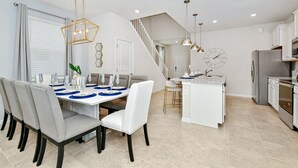 A modern kitchen with white cabinets, a stainless steel refrigerator, and a built-in oven.