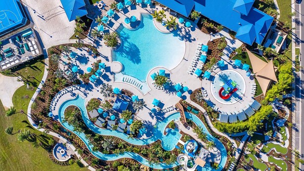 An aerial view of a resort with a large central pool, multiple water slides, and sun loungers.