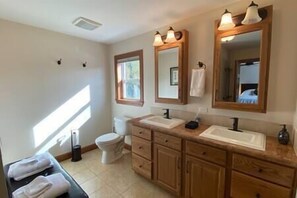 A bathroom with two sinks, a toilet, and a vanity with drawers. - Tripoli Shores Riverfront Retreat (Cape Vincent)