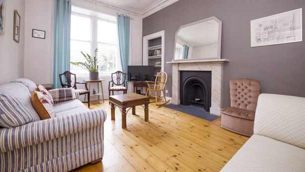 A living room with a sofa, chairs, a fireplace, and a television. - Splendid Apartment near Haymarket (Edinburgh)