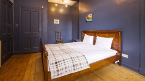 A bedroom with a wooden bed, a dark blue wall, and a wooden floor. - Splendid Apartment near Haymarket (Edinburgh)
