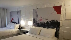 A hotel room with two beds, white bedding, and abstract wall art. - Cozy Studio at the Orlando theme parks Neighborhood (Kissimmee)