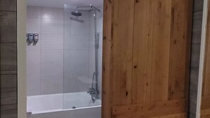 A bathroom with a wooden door, a bathtub, and a shower area. - Cozy Studio at the Orlando theme parks Neighborhood (Kissimmee)