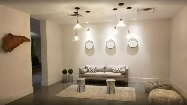 A modern living room with a sofa, decorative clocks, and pendant lighting. - Cozy Studio at the Orlando theme parks Neighborhood (Kissimmee)