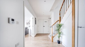 Ein moderner Flur mit Holzboden, einer Treppe mit Holzgeländer und einer Blumentopf-Pflanze.