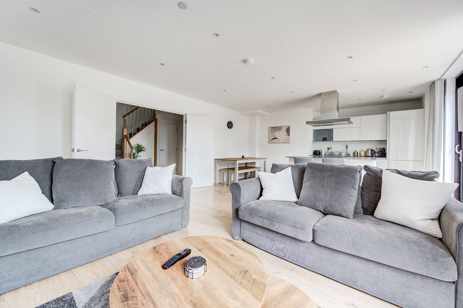 A spacious living room with two grey sofas, a wooden coffee table, and a remote control.