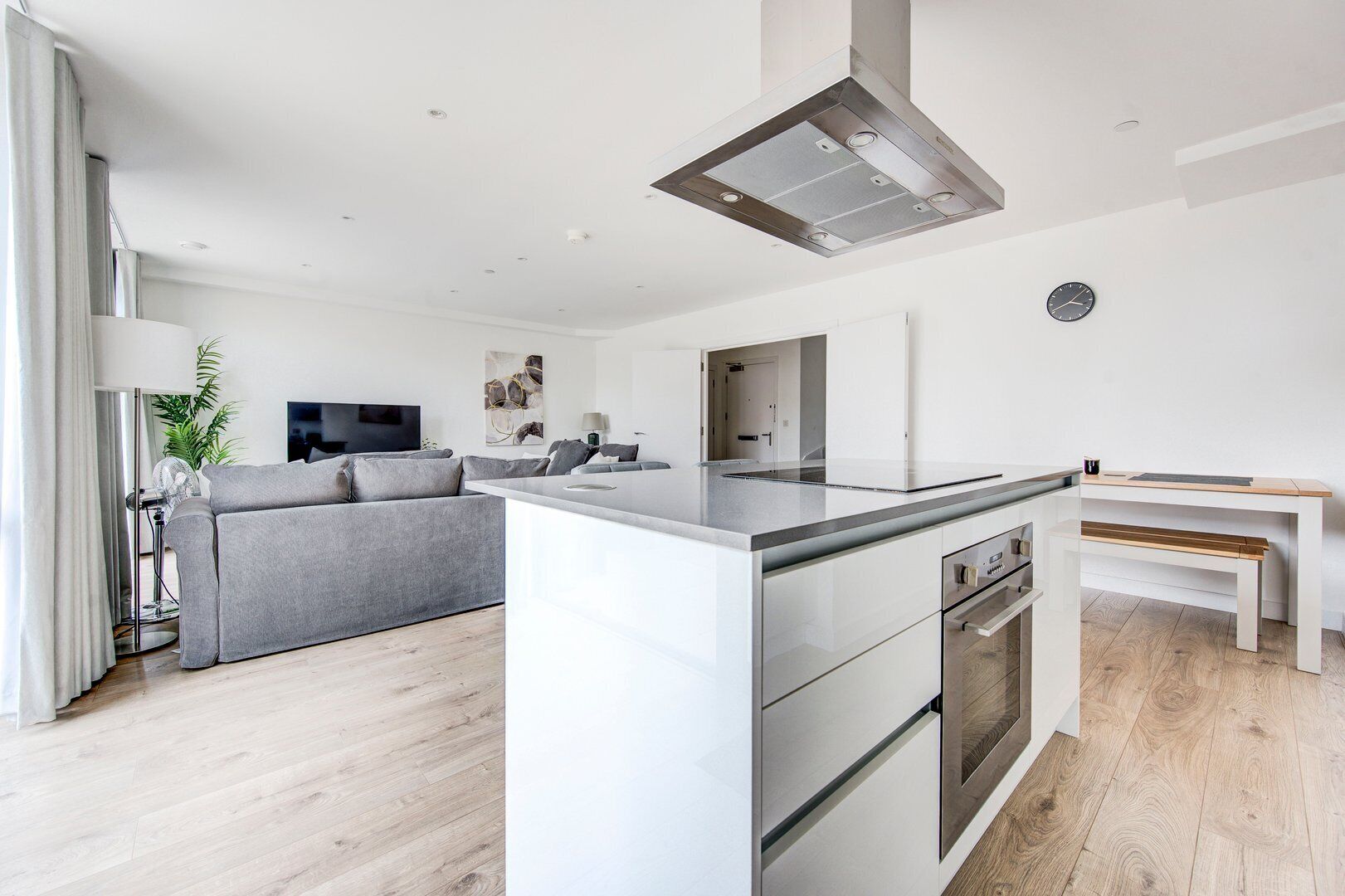 A modern kitchen with a central island, a built-in oven, and a dining area with a bench.
