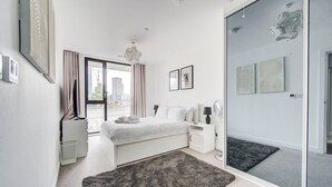 Ein modernes Schlafzimmer mit einem großen Bett, einem Nachttisch, einer Stehlampe und einem großen Fenster mit Vorhängen.