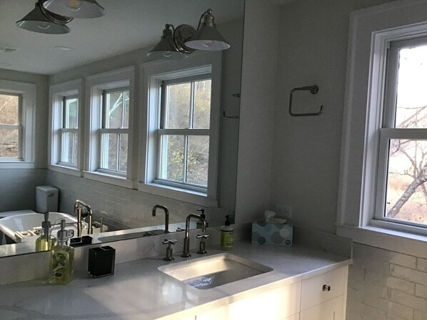 A bathroom with a large mirror, a sink, and a window.