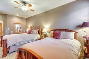 A bedroom with two beds, a ceiling fan, bedside lamps, and a mirror on the wall. - Unwind Fireside: Spacious Torreon Cabin w/ Deck! (Show Low)