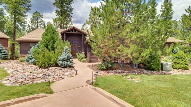 A residential property with a well-maintained lawn, a stone pathway leading to the entrance, and a variety of trees and shrubs. - Unwind Fireside: Spacious Torreon Cabin w/ Deck! (Show Low)