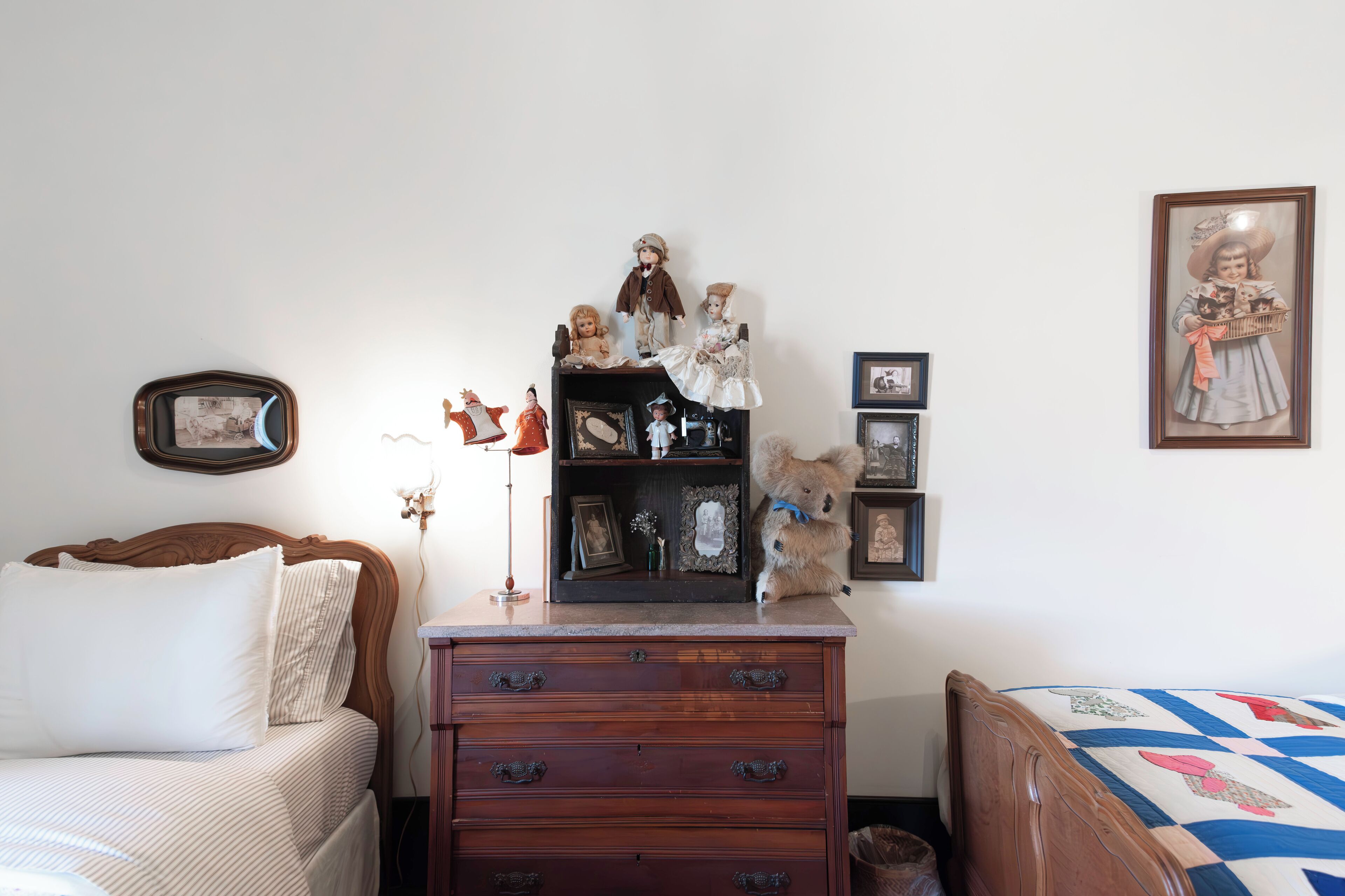 A bedroom with a bed, dresser, and a shelf with figurines.