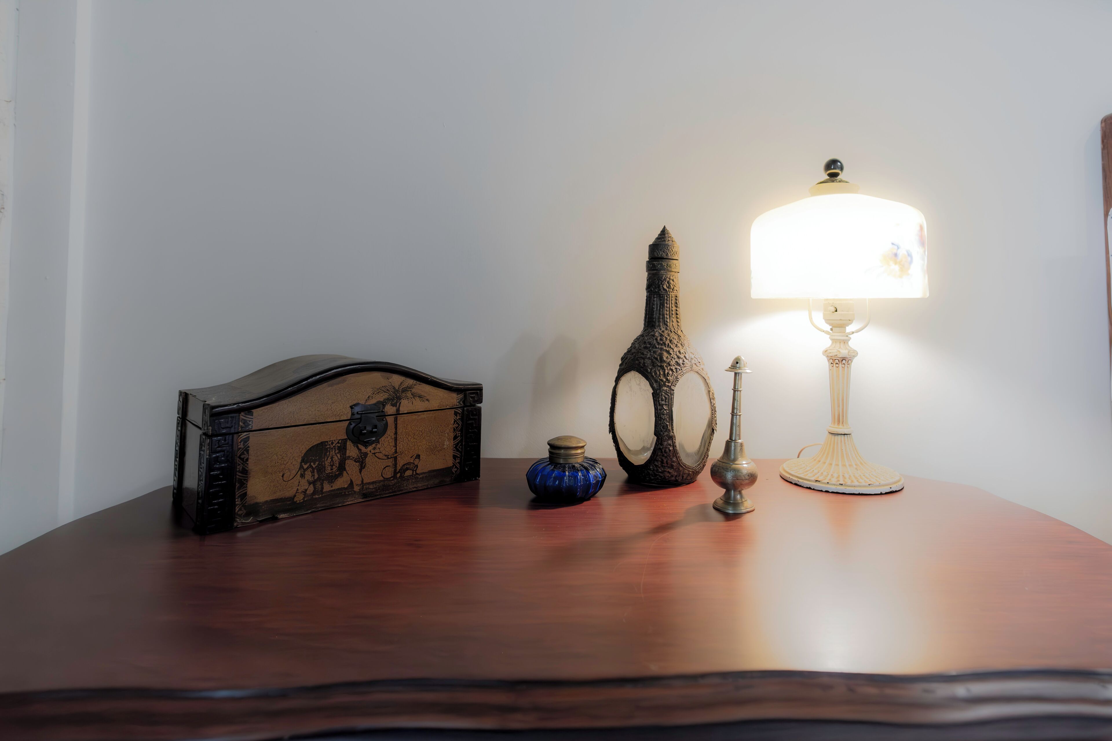 A wooden table with a decorative box, a blue vase, a lamp, and a mirror.