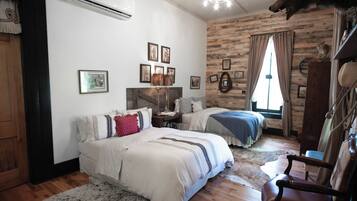 A cozy room with two beds, a wooden floor, a mounted animal head, and a rustic wall.