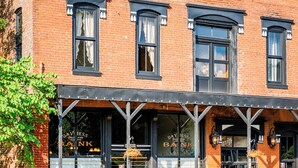 A brick building with a covered front porch, large windows, and a sign that reads "DAVIESS BANK". - Beard and Lady Inn (Chester)