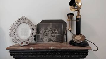 A wooden shelf with a framed photograph, a decorative mirror, and a vintage telephone.