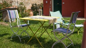 An outdoor seating area with a table and chairs, a bottle, and glasses. - GuestHost - Cozy apartment that hosts up to 4 people, located in a shared villa in the hilly Umbrian countryside. We are in the Ponte Rio hamlet, an extremely quiet and relaxing area in which to stay in close contact with nature but at the same time not  (Perugia)