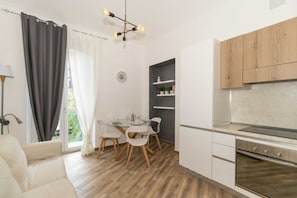A modern kitchen with white cabinets, a built-in oven, and a dining area with a glass table and chairs.