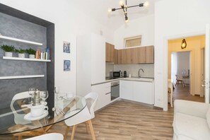 Una cocina moderna con armarios blancos, microondas y cafetera.