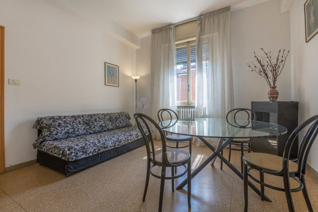 Un'area living con un divano, un tavolo da pranzo con piano in vetro e sedie.