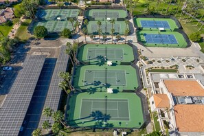 Luchtbeeld van een tennisterreincomplex met meerdere banen, parkeerplaatsen en omliggend groen.